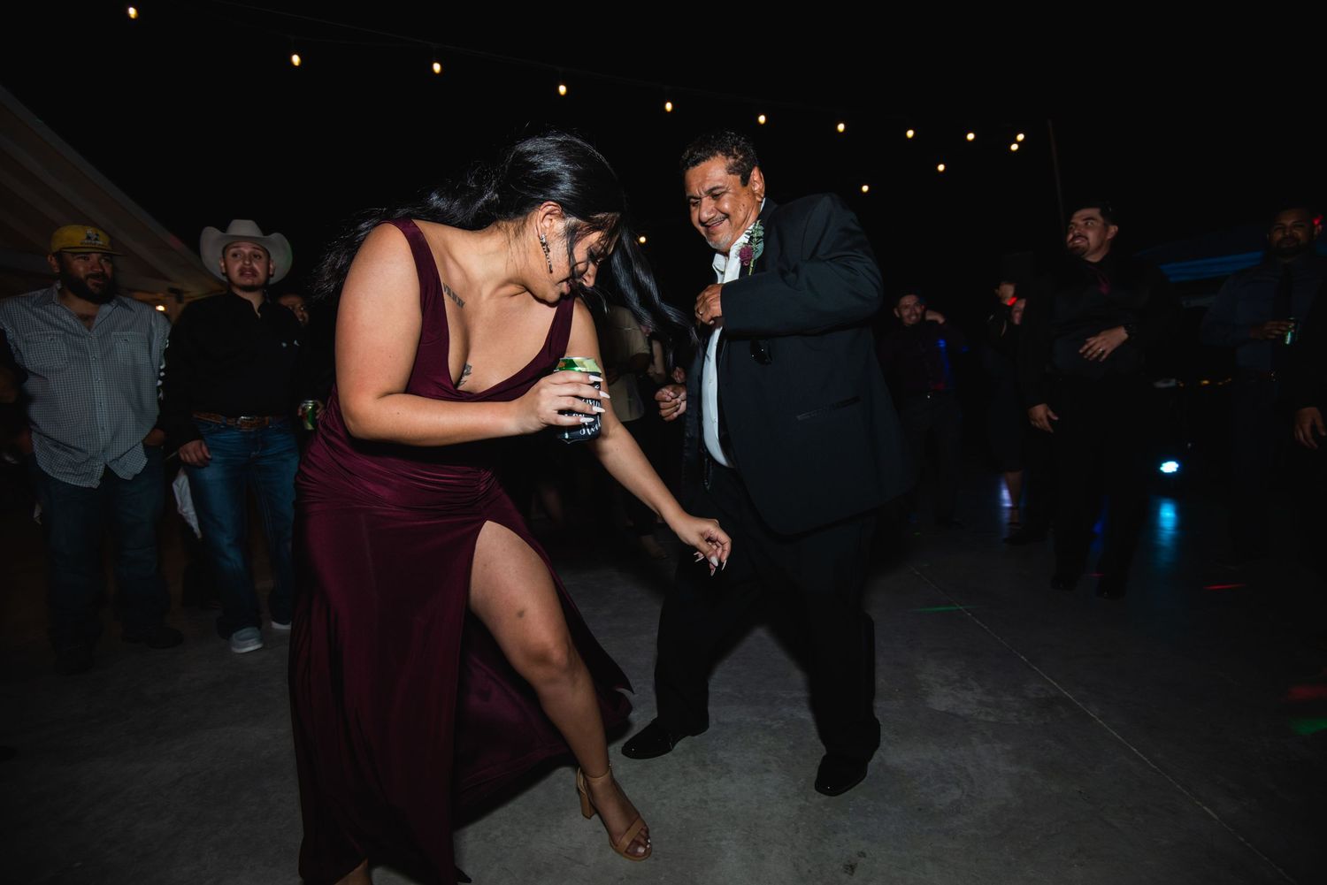 Party guests dance enthusiastically on a dark dance floor at a celebration.