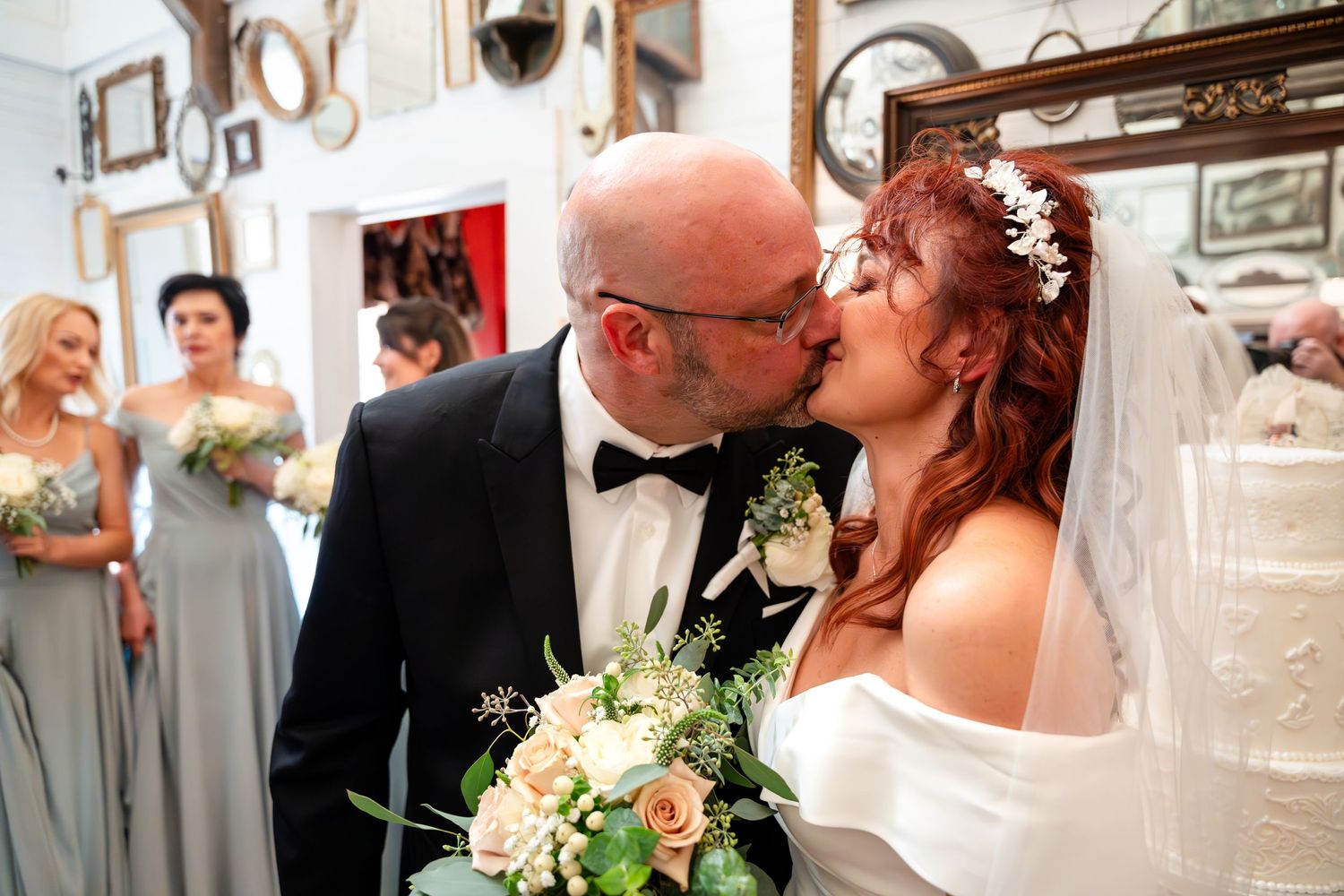 A wedding moment captured with bridesmaids in gray dresses looking on in a mirror-decorated venue.