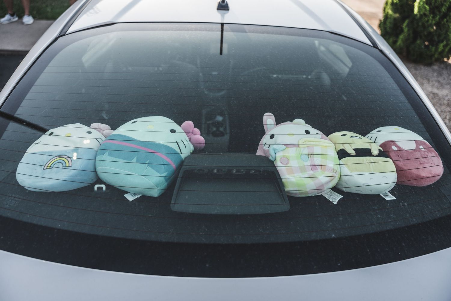 Car rear window displaying colorful Easter bunny decorations.