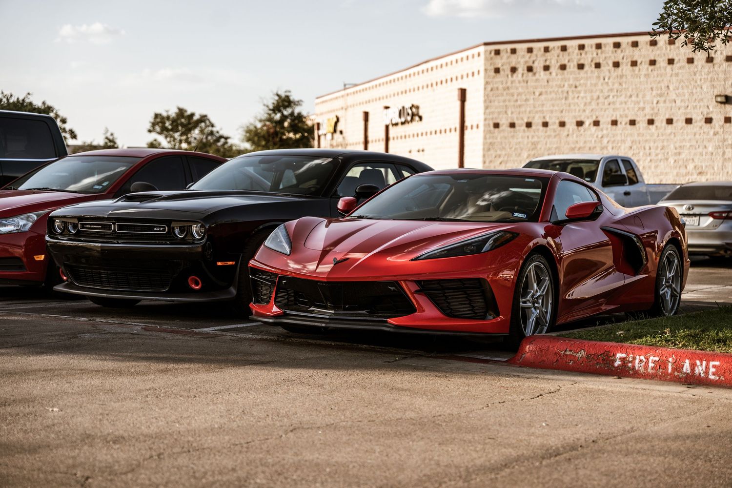 Red Chevrolet Corvette C8 parked next to a black Dodge Challenger.