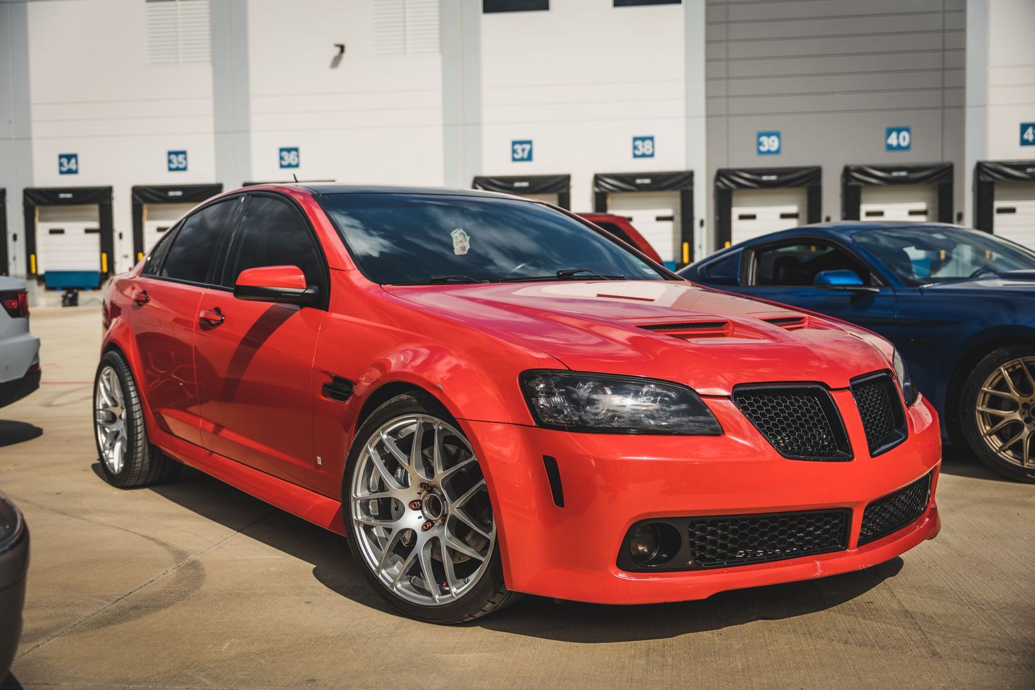 Bright red Pontiac G8 sport sedan with custom wheels and performance modifications.
