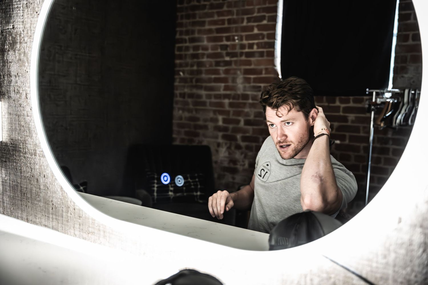Mirror reflection shows person adjusting headphones in recording studio setting.