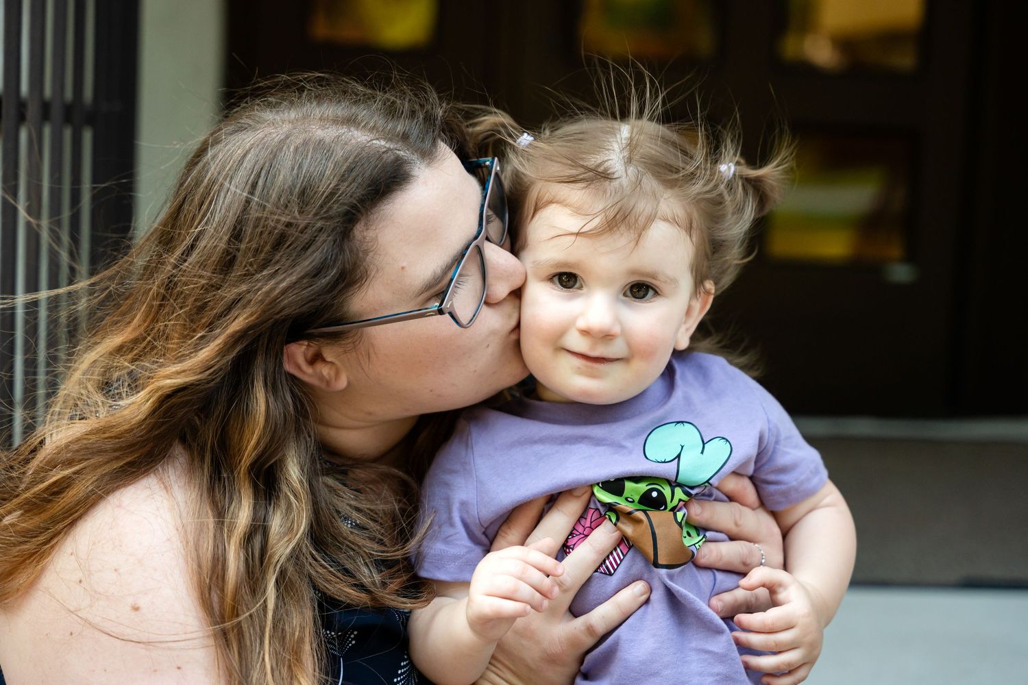 A tender moment captured outdoors with a child wearing a purple graphic t-shirt.