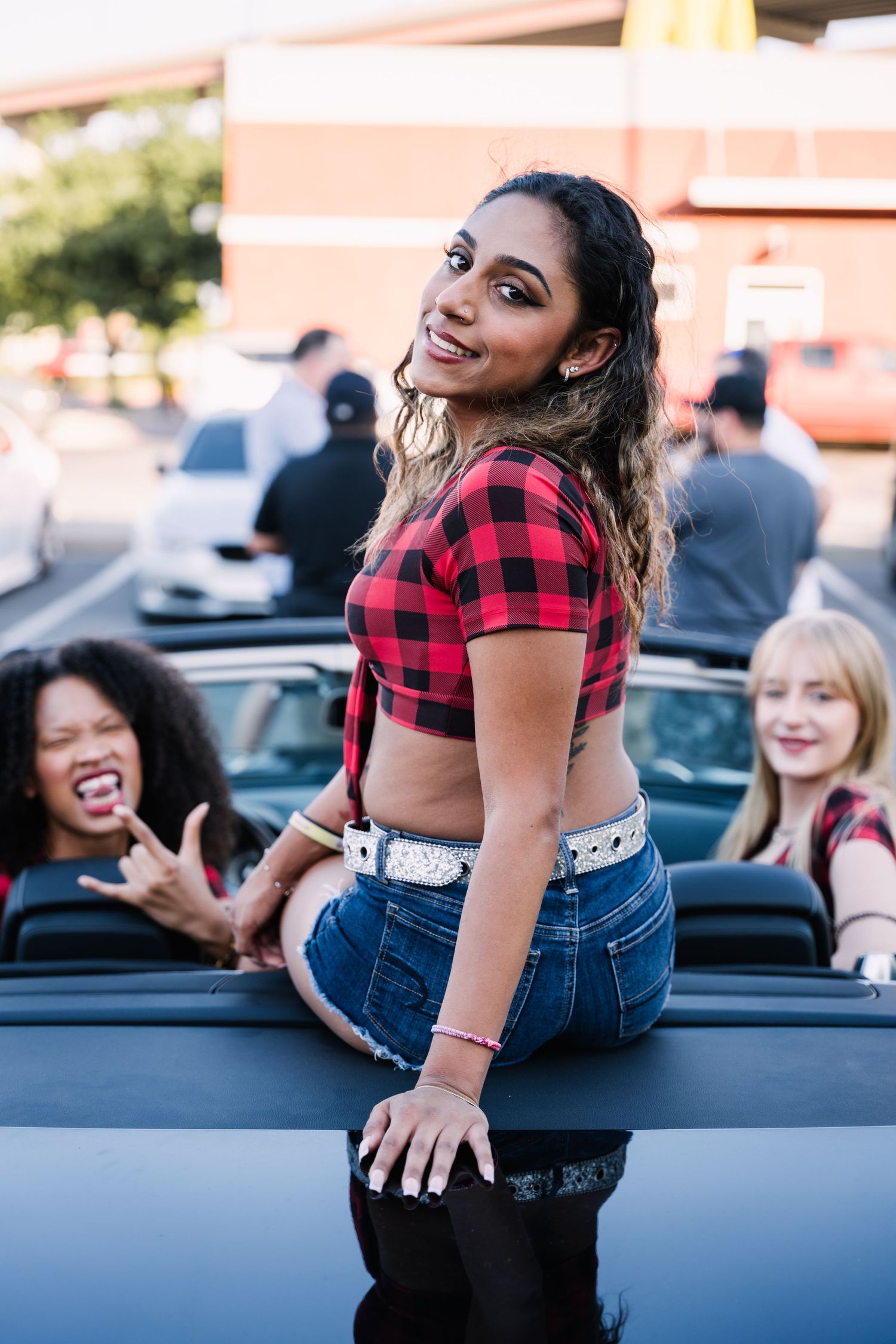 Casual summer fashion photoshoot in parking lot with plaid shirt and denim shorts.
