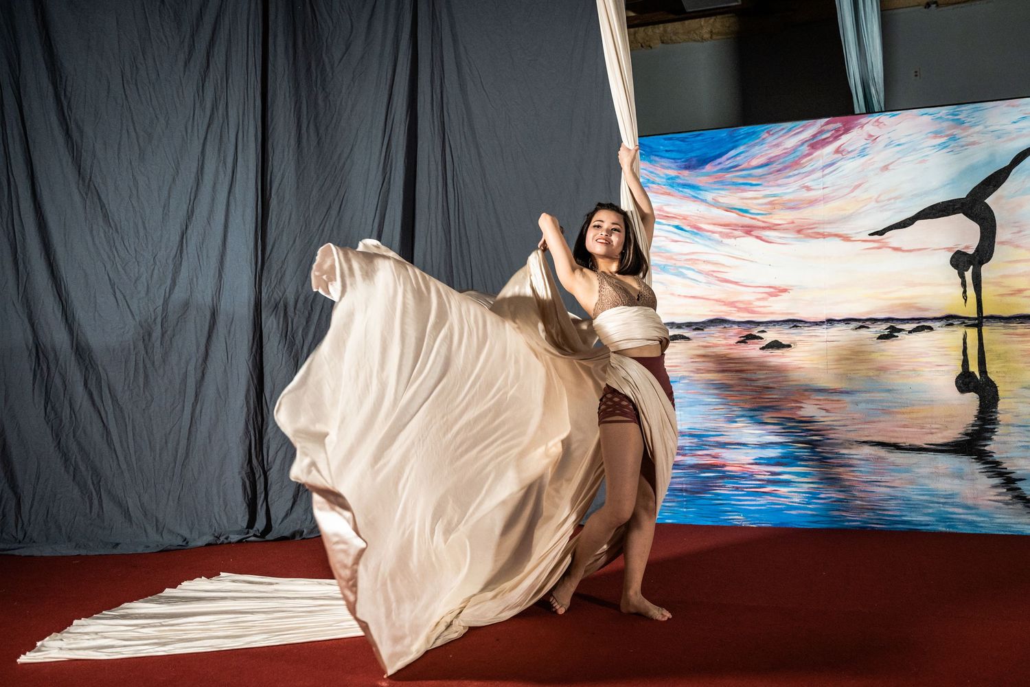 A series of abstract dance performance photos showing flowing white fabric against a dark backdrop and blue lighting.