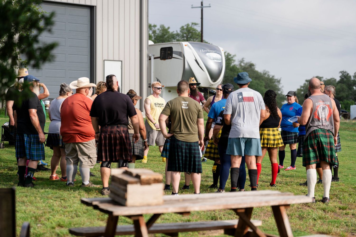 A group of people gathered outside a building watching a demonstration or presentation in a rural setting.