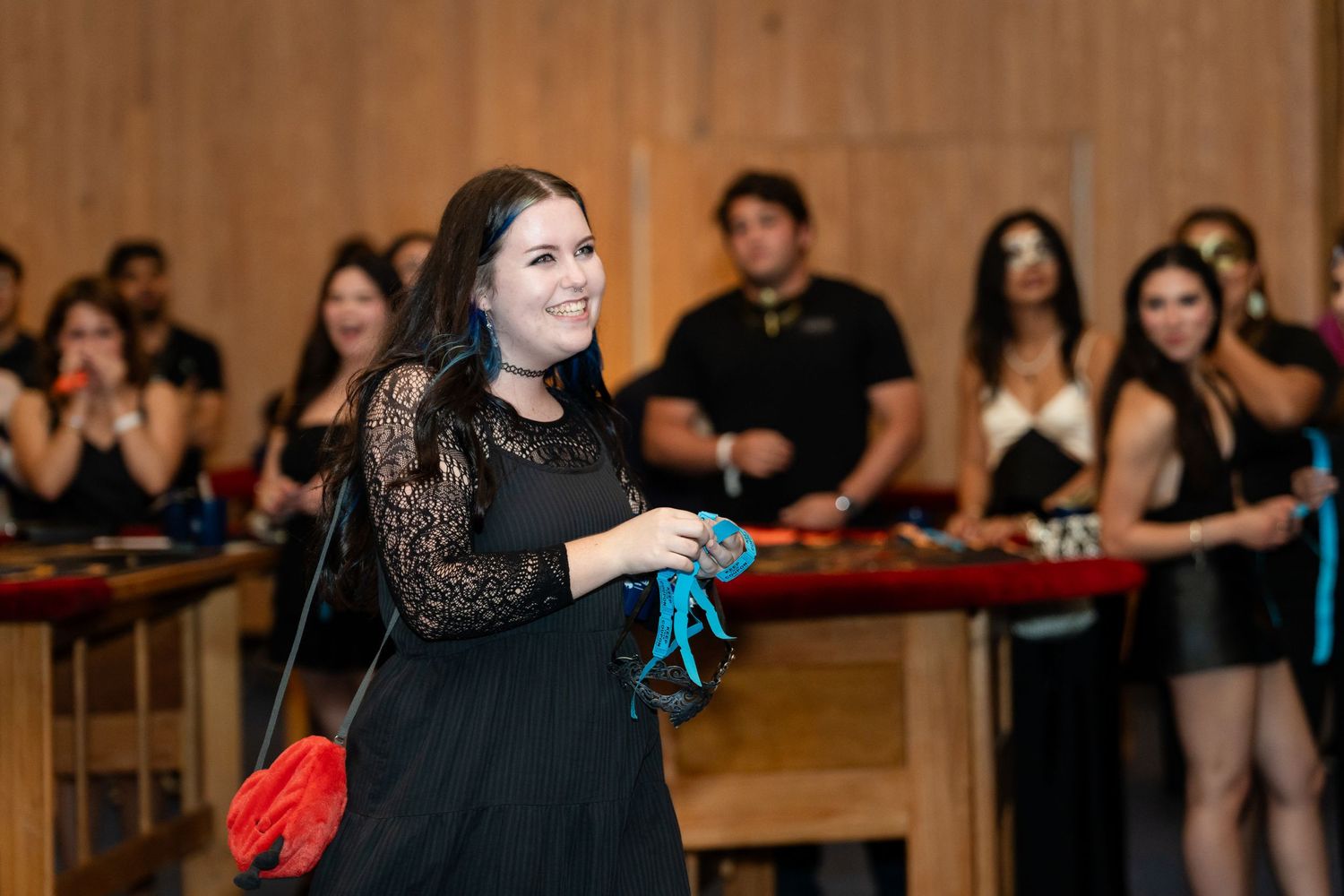 A person in black holding props while performing at an indoor event.