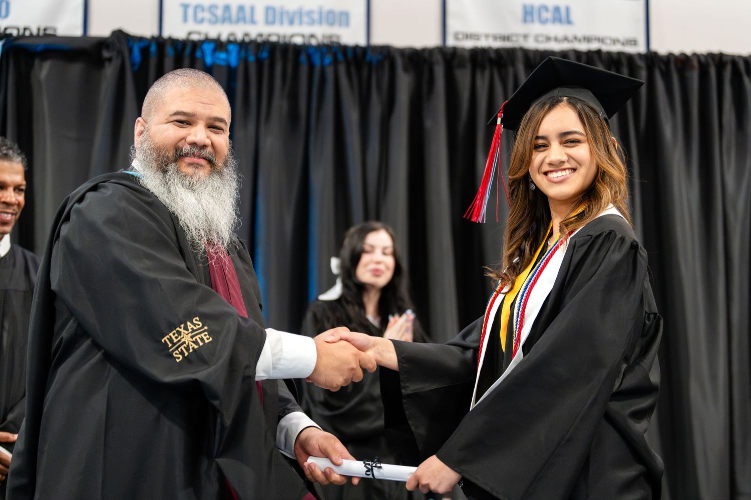 Graduate with honors cords receives diploma during commencement ceremony.