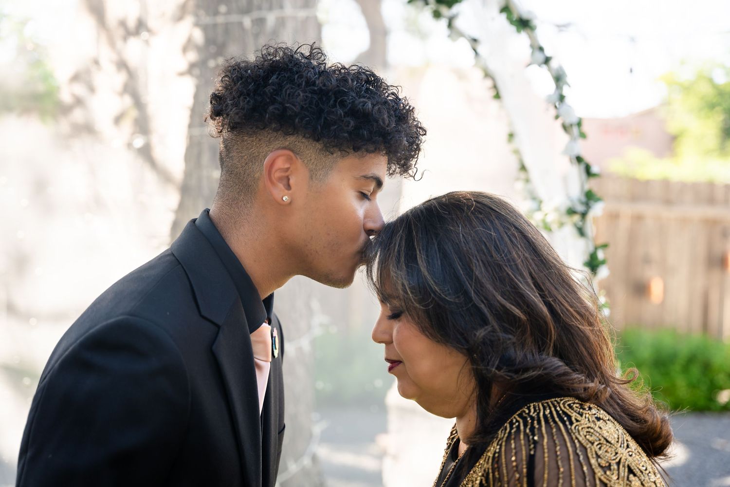 An intimate close-up of two people sharing a quiet moment under garden greenery.