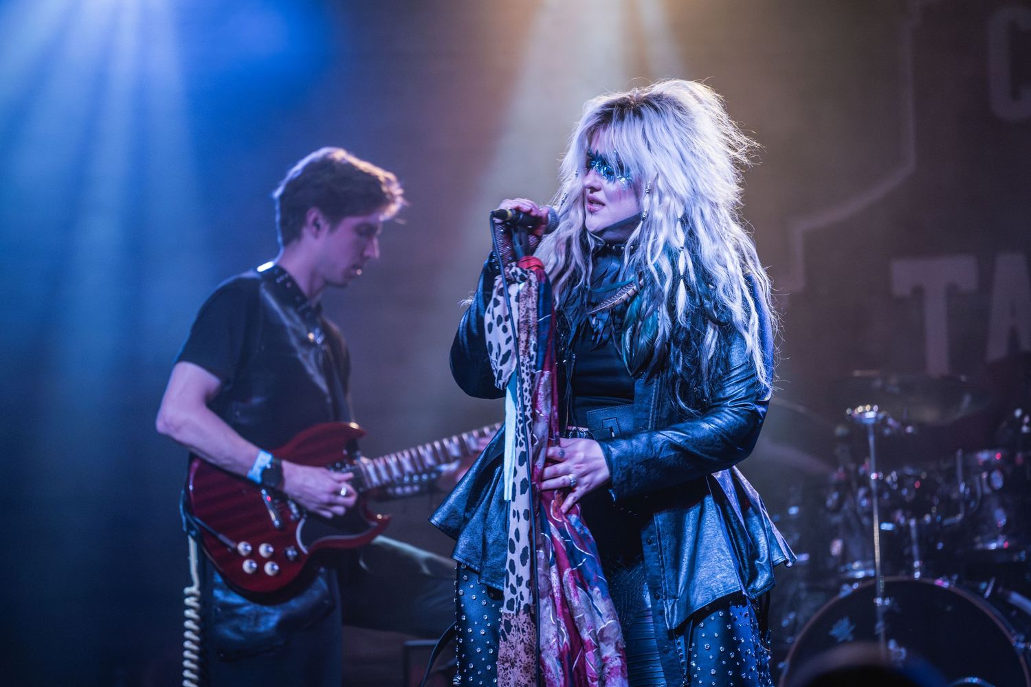 Rock band performs on stage with dramatic blue lighting and smoke effects during live concert performance.
