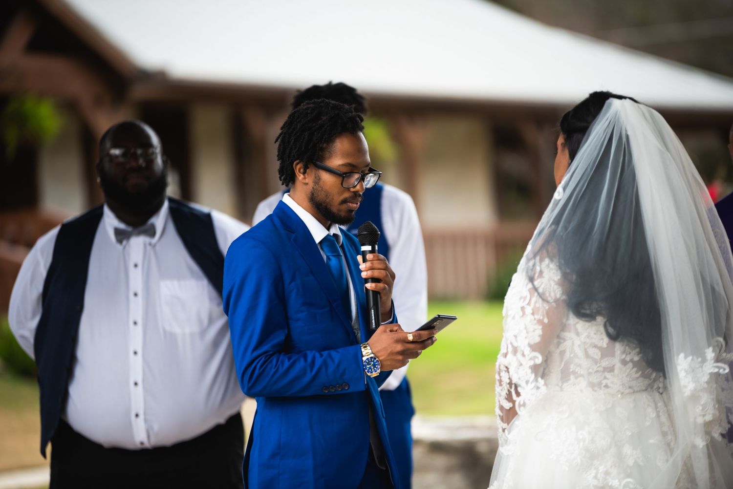Emotional wedding vow reading during outdoor ceremony with white tent in background.