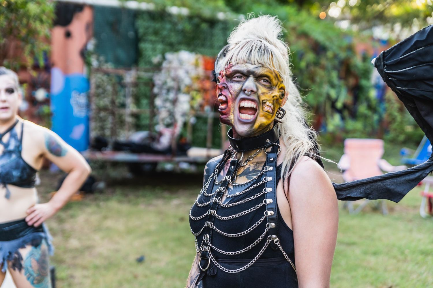 Performer in dramatic theatrical makeup and chains performing at outdoor event.