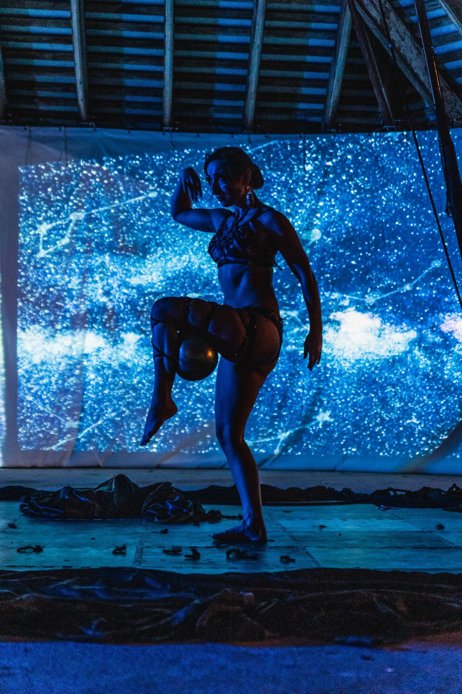 Dynamic dance pose silhouetted against ethereal blue starry backdrop.