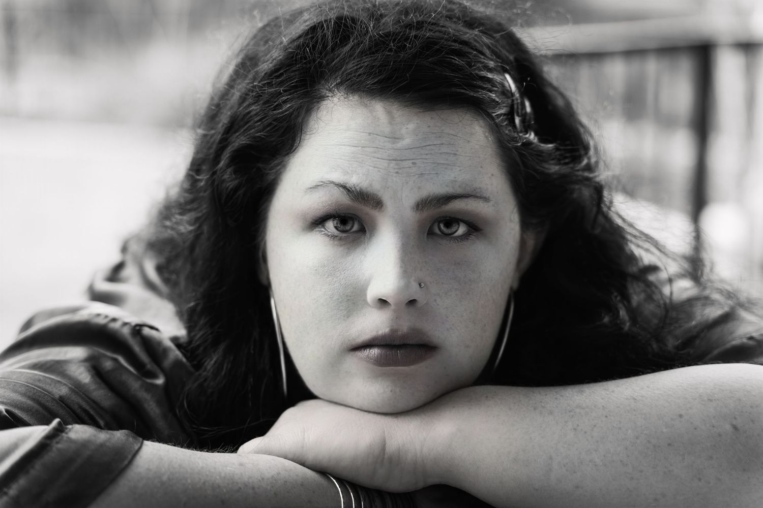 Black and white portrait of a young woman resting her head on her hand with dark wavy hair.