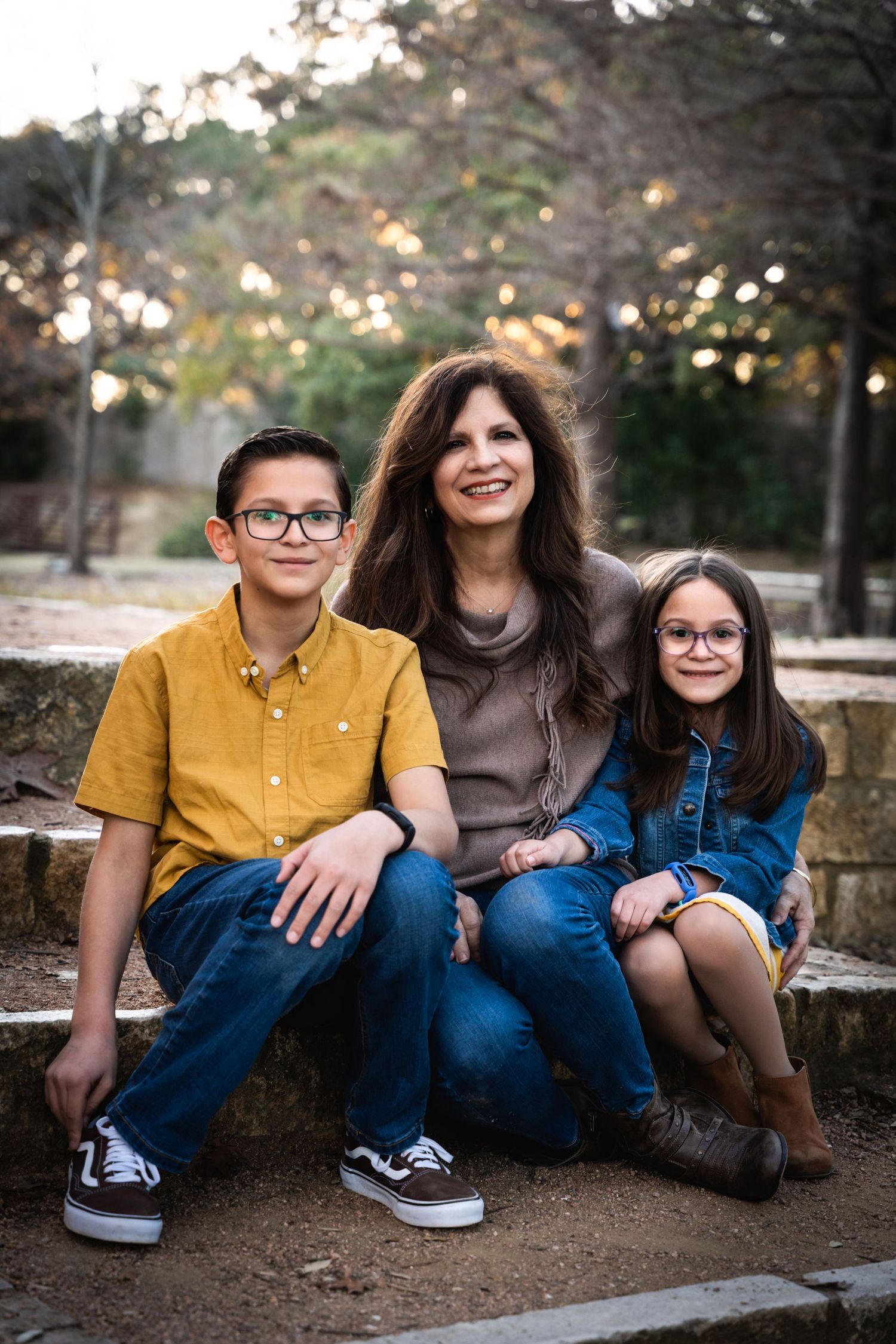 A casual outdoor family portrait on stone steps during golden hour.
