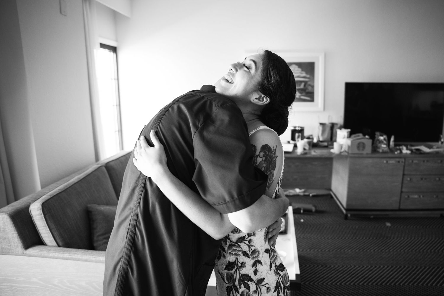Two people embrace in an emotional black and white moment indoors.