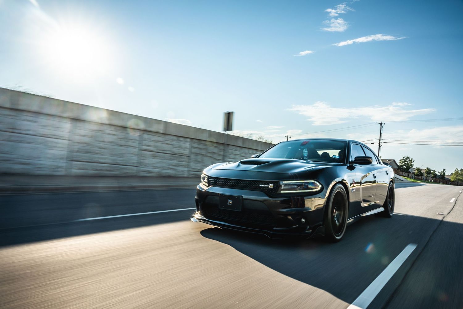 Black Dodge Charger speeding on highway with motion blur effect.