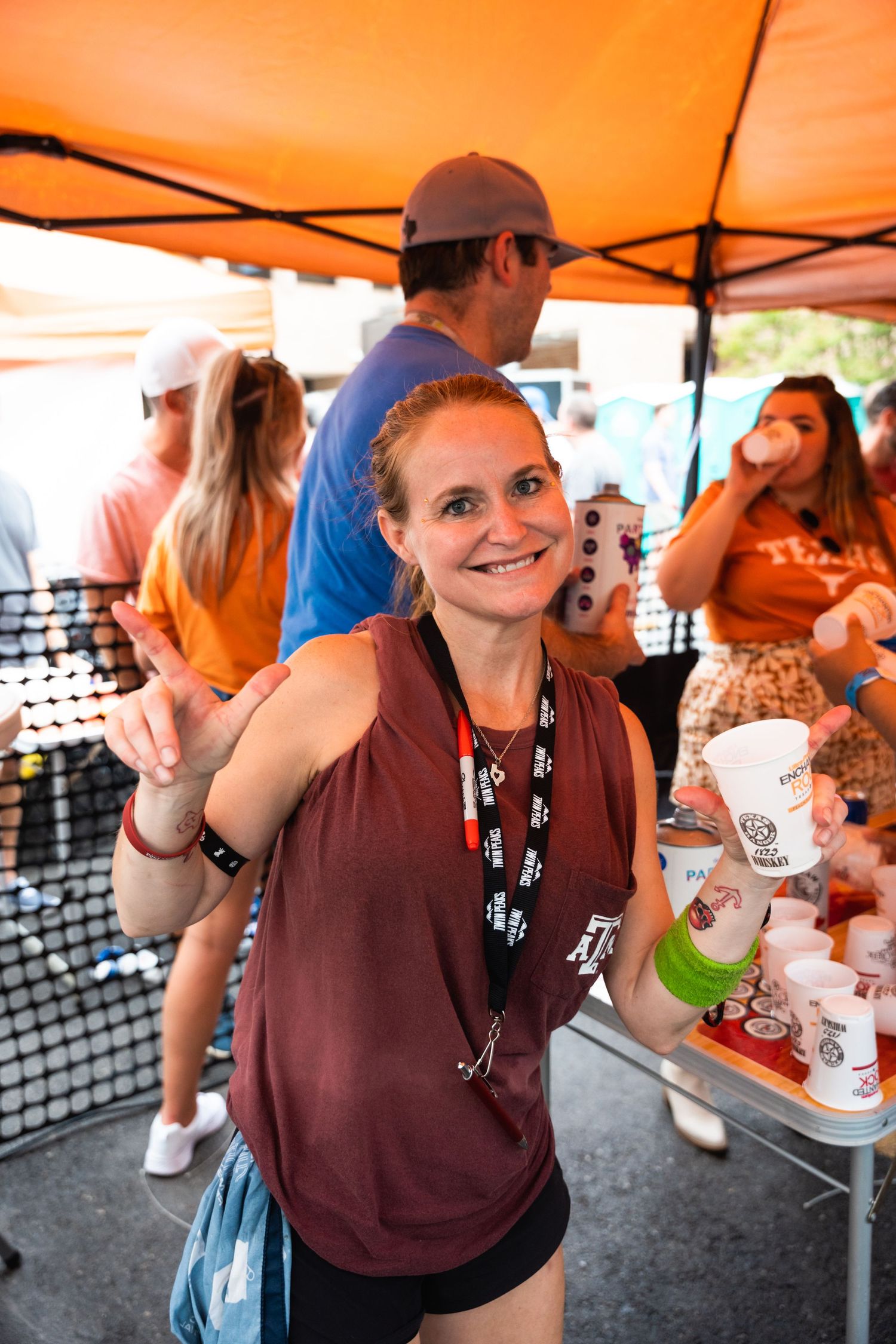 Event attendee enjoying festivities under an orange tent with drinks.