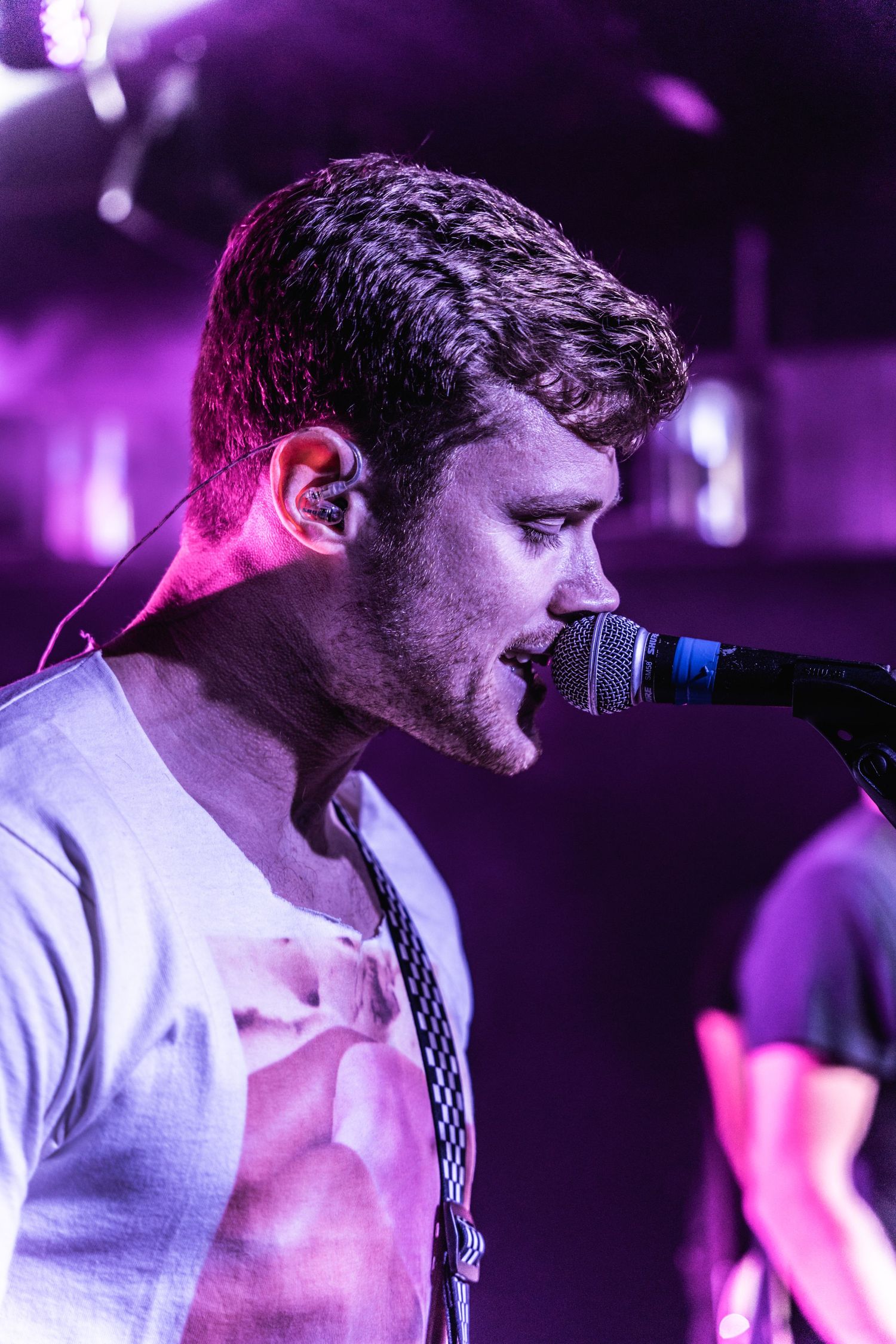 Singer performs passionately into microphone under purple stage lighting effects.