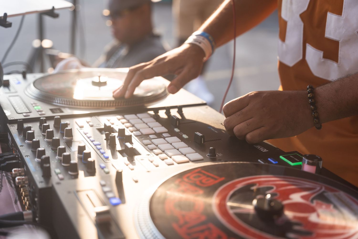 Close up of DJ hands mixing music on professional turntable equipment.