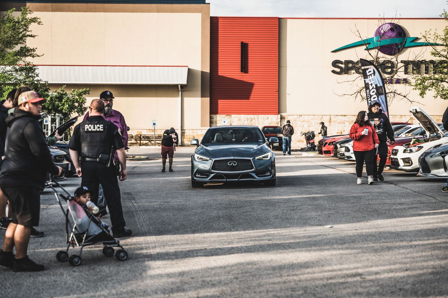 Cars gathered at a parking lot meet-up outside a Supercenter store.