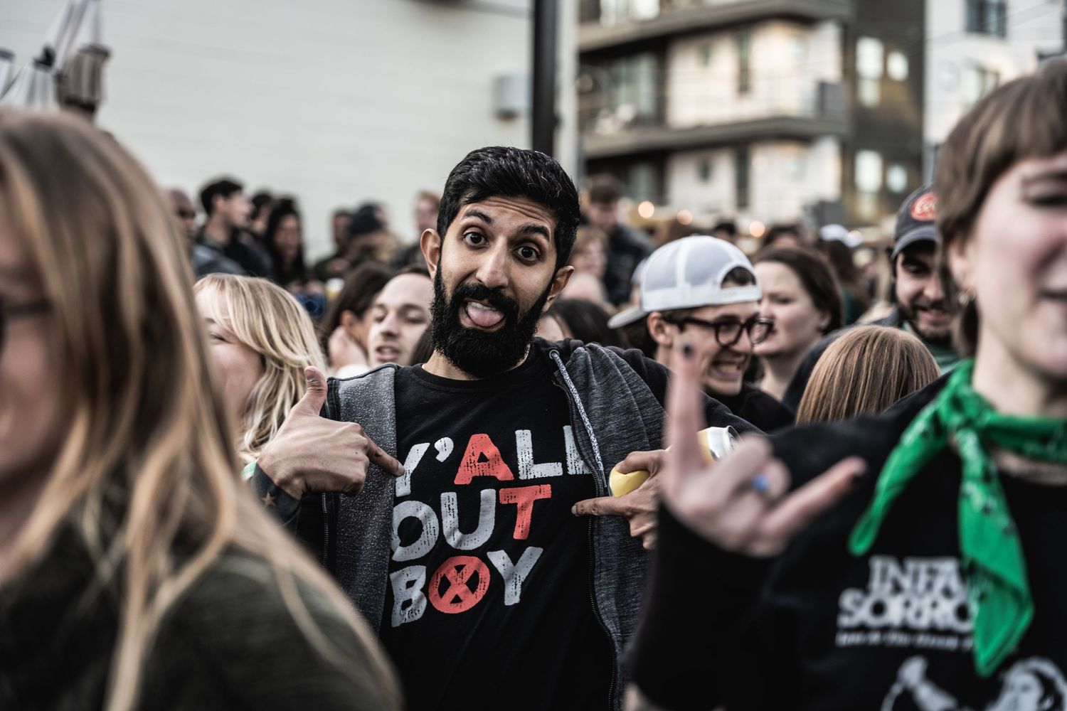 Energetic crowd at outdoor music festival with person in black t-shirt showing enthusiasm.