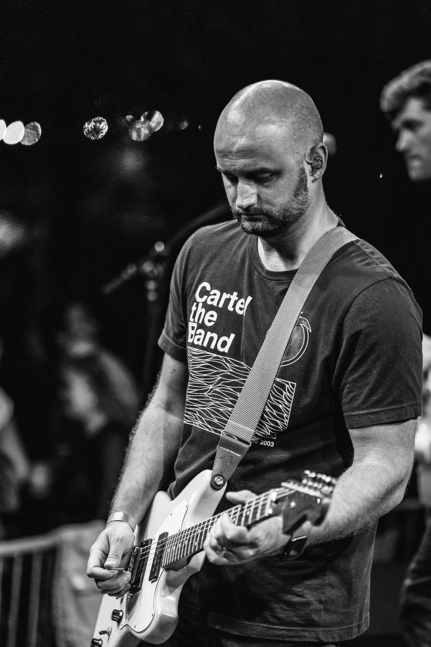 Black and white photo of guitarist playing electric guitar during performance.