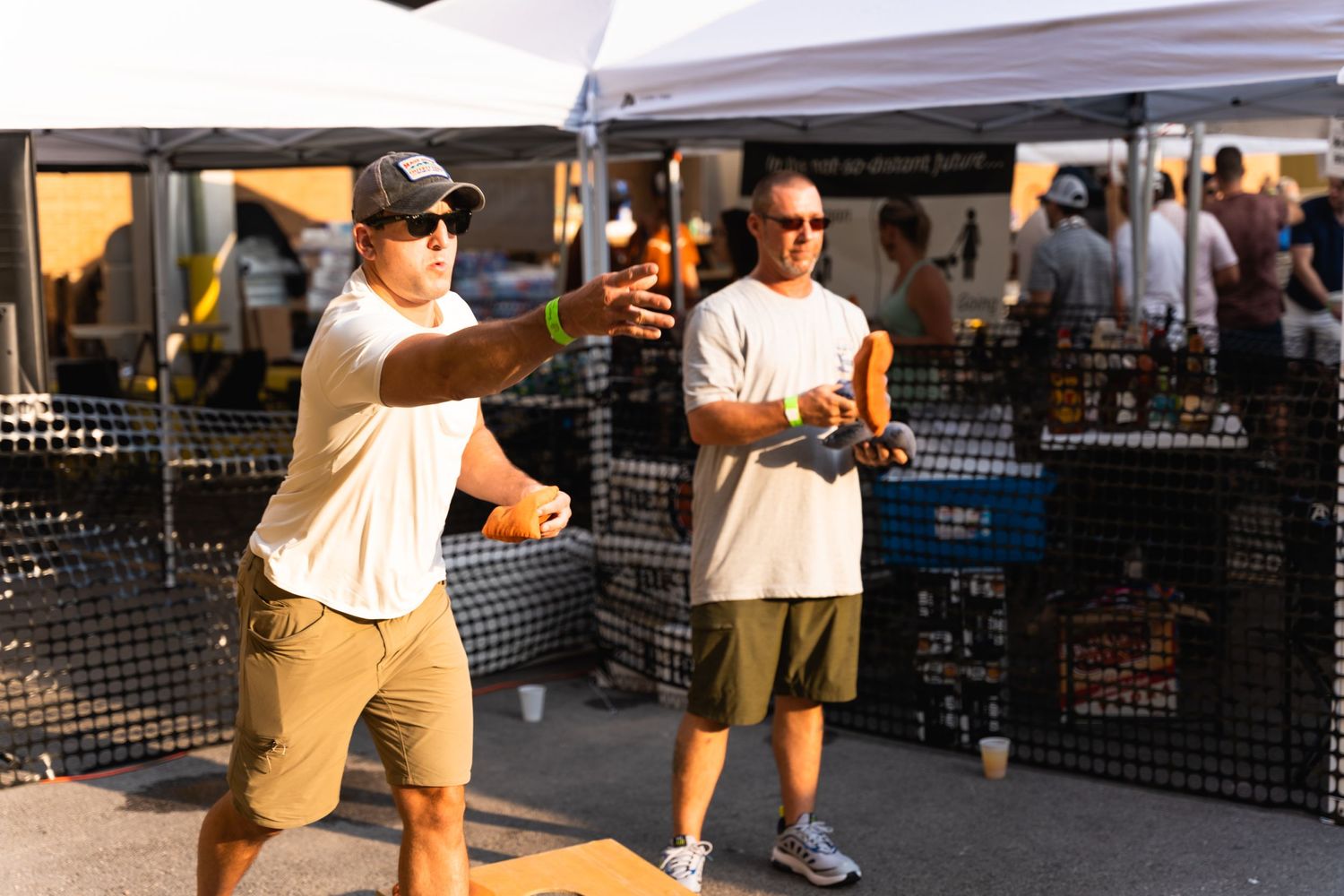People play games at an outdoor event under white canopy tents.