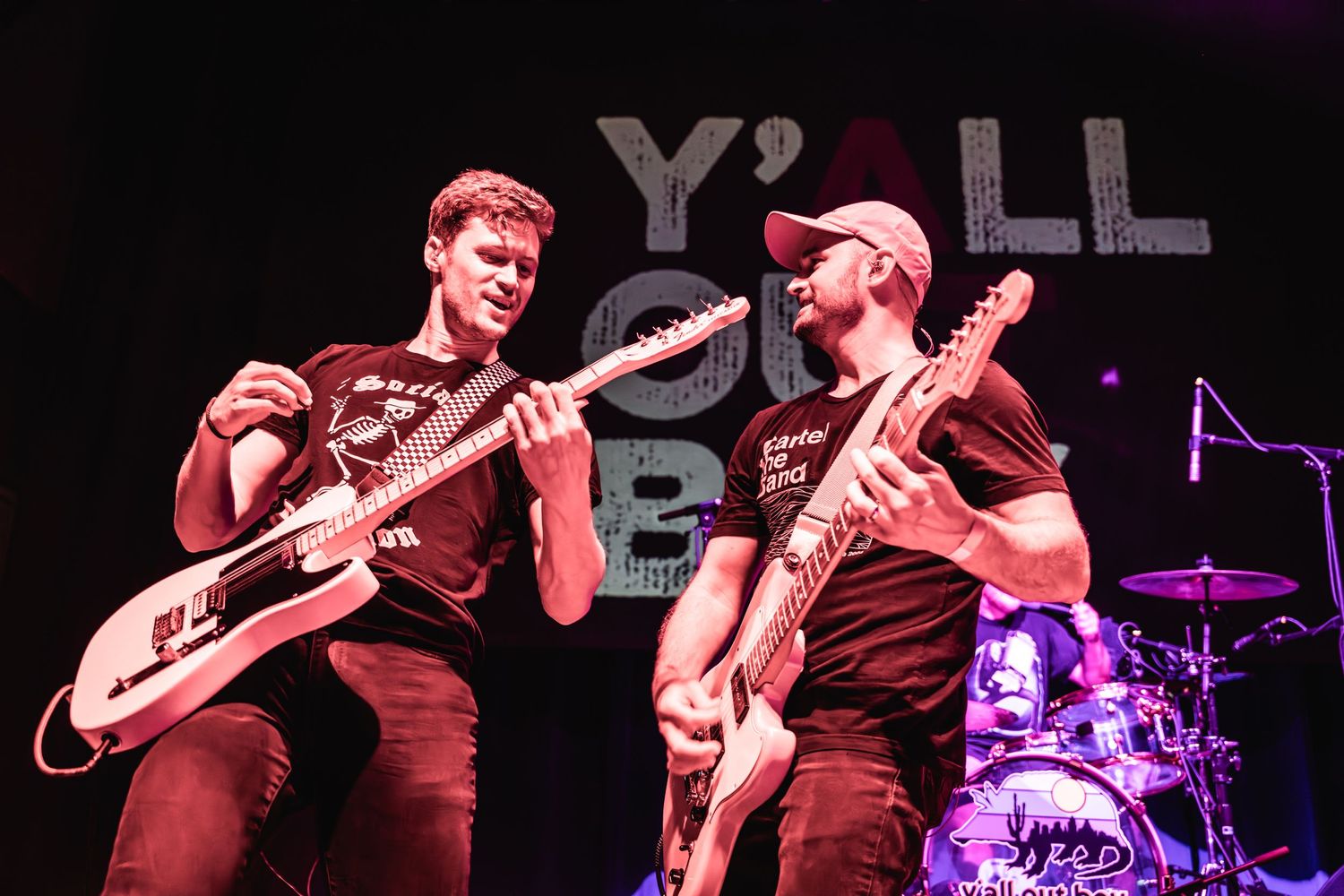 Two musicians playing guitars perform together on stage during a rock concert.