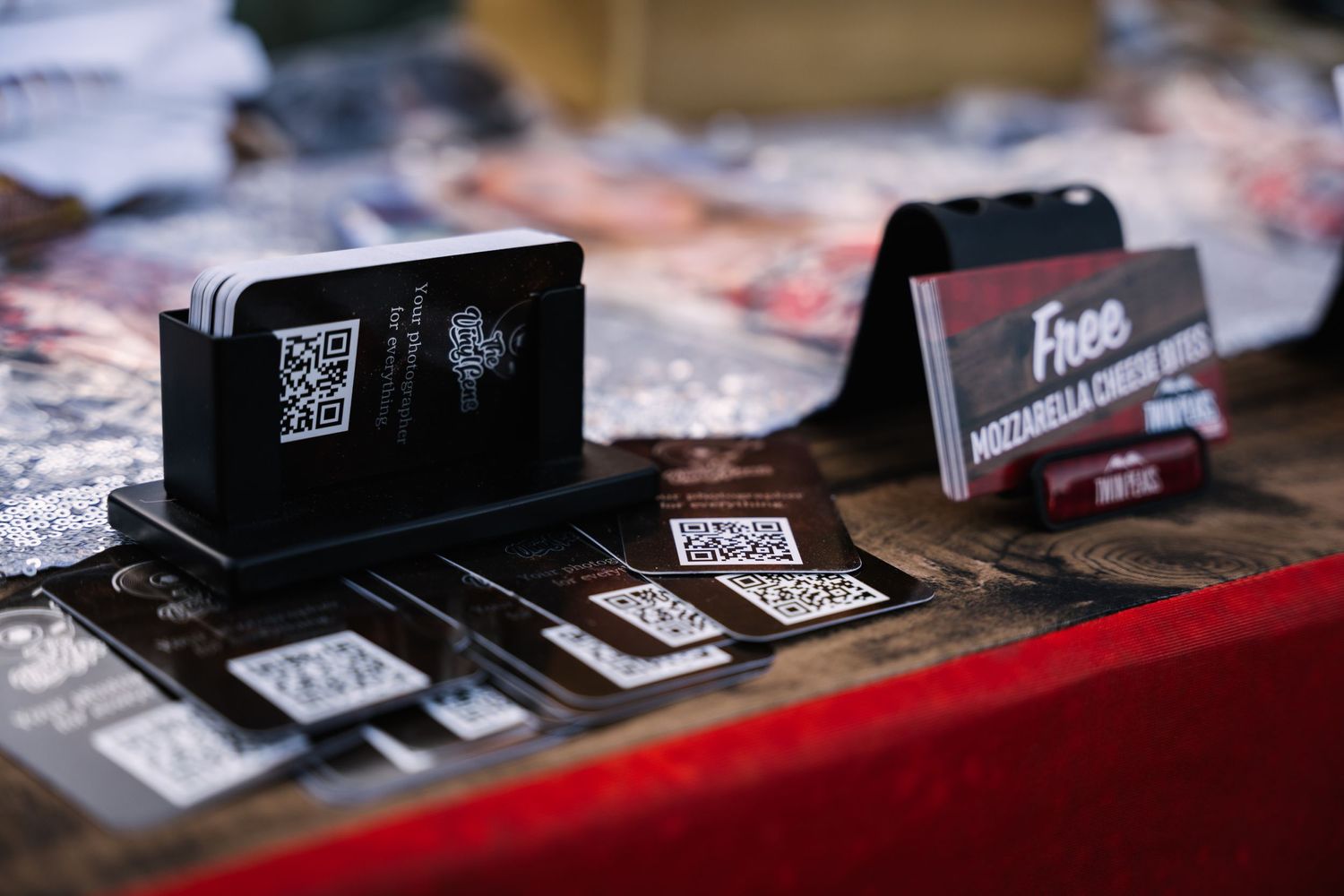 Close-up of business cards and QR codes displayed on a red table surface.