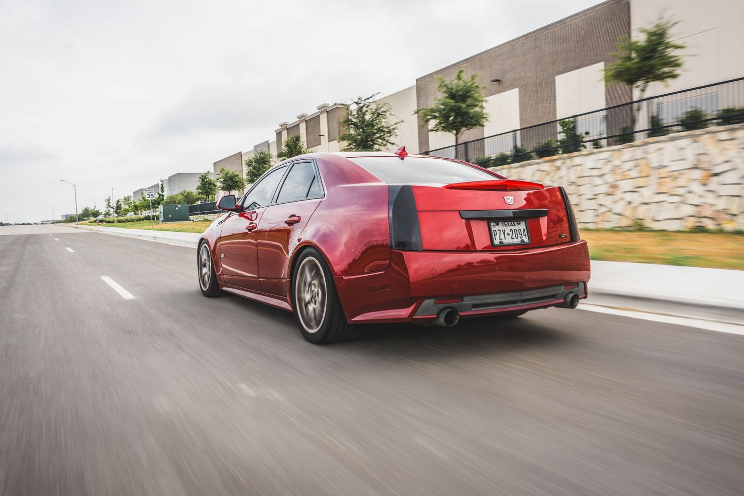 Red Cadillac CTS-V sport sedan photographed from rear quarter while driving.