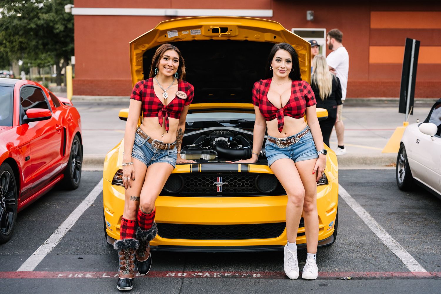 Yellow Mustang with open hood at a car meet.