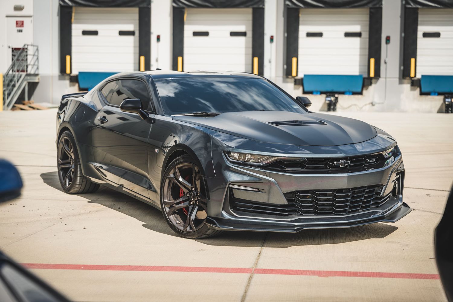 Modified black Chevrolet Camaro with aggressive styling and red accents parked at loading dock.