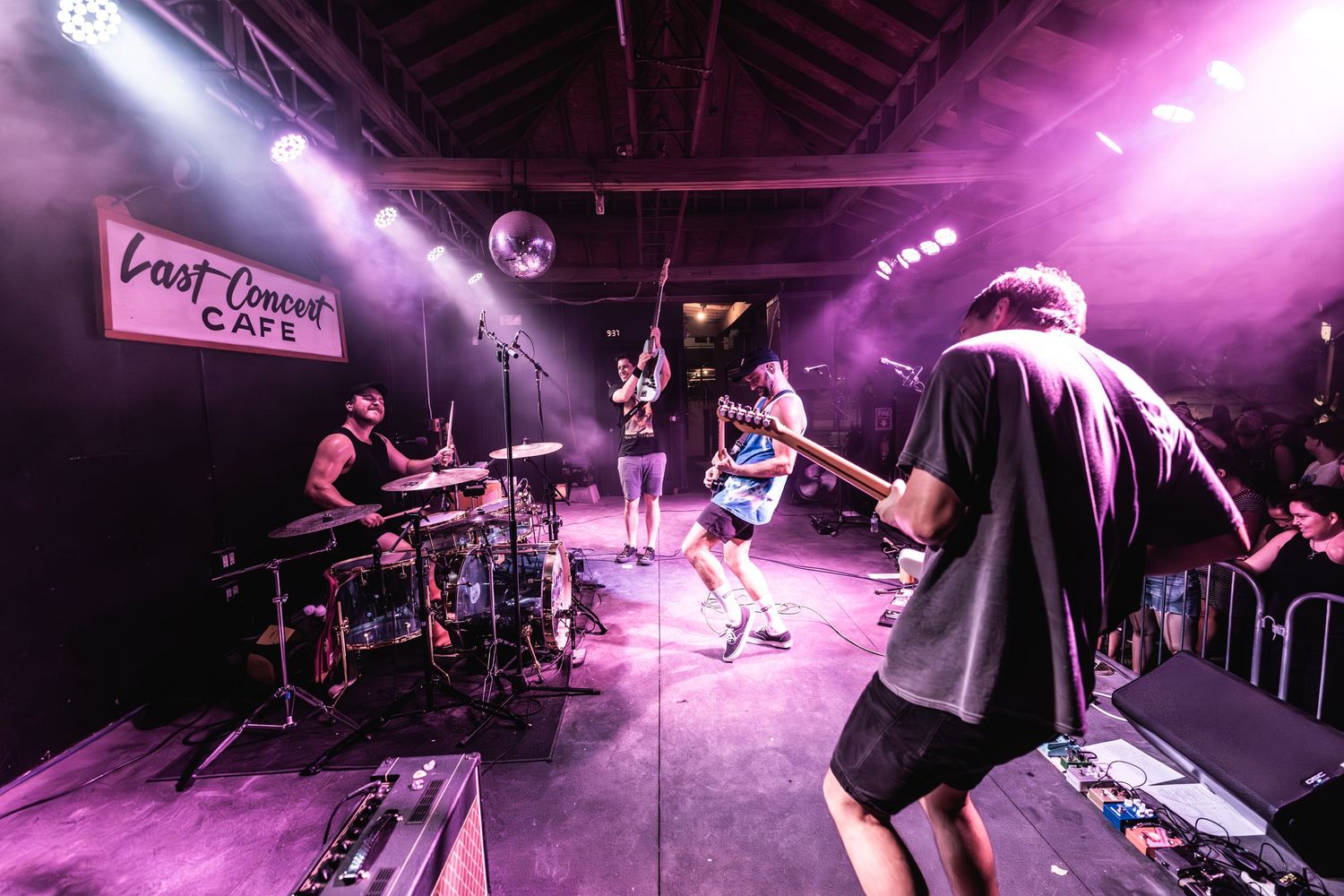 Band performs on stage with pink lighting effects at Post Concert Cafe.