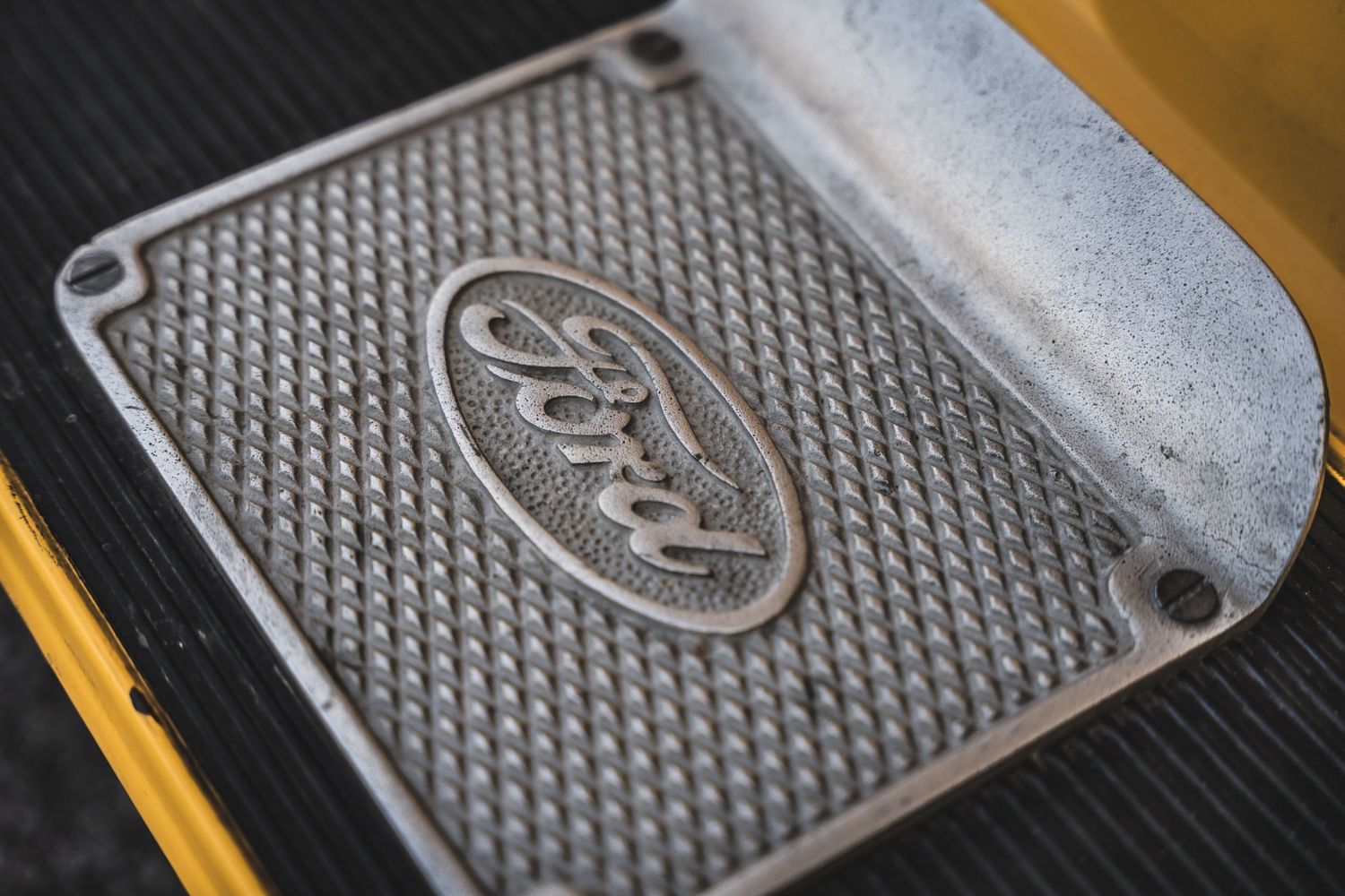 Close-up detail of a textured metal Ford logo badge with diamond pattern design.