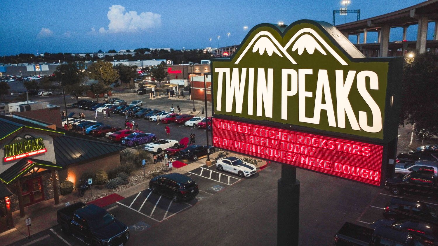 Twin Peaks restaurant sign illuminated at night with parking lot visible below.