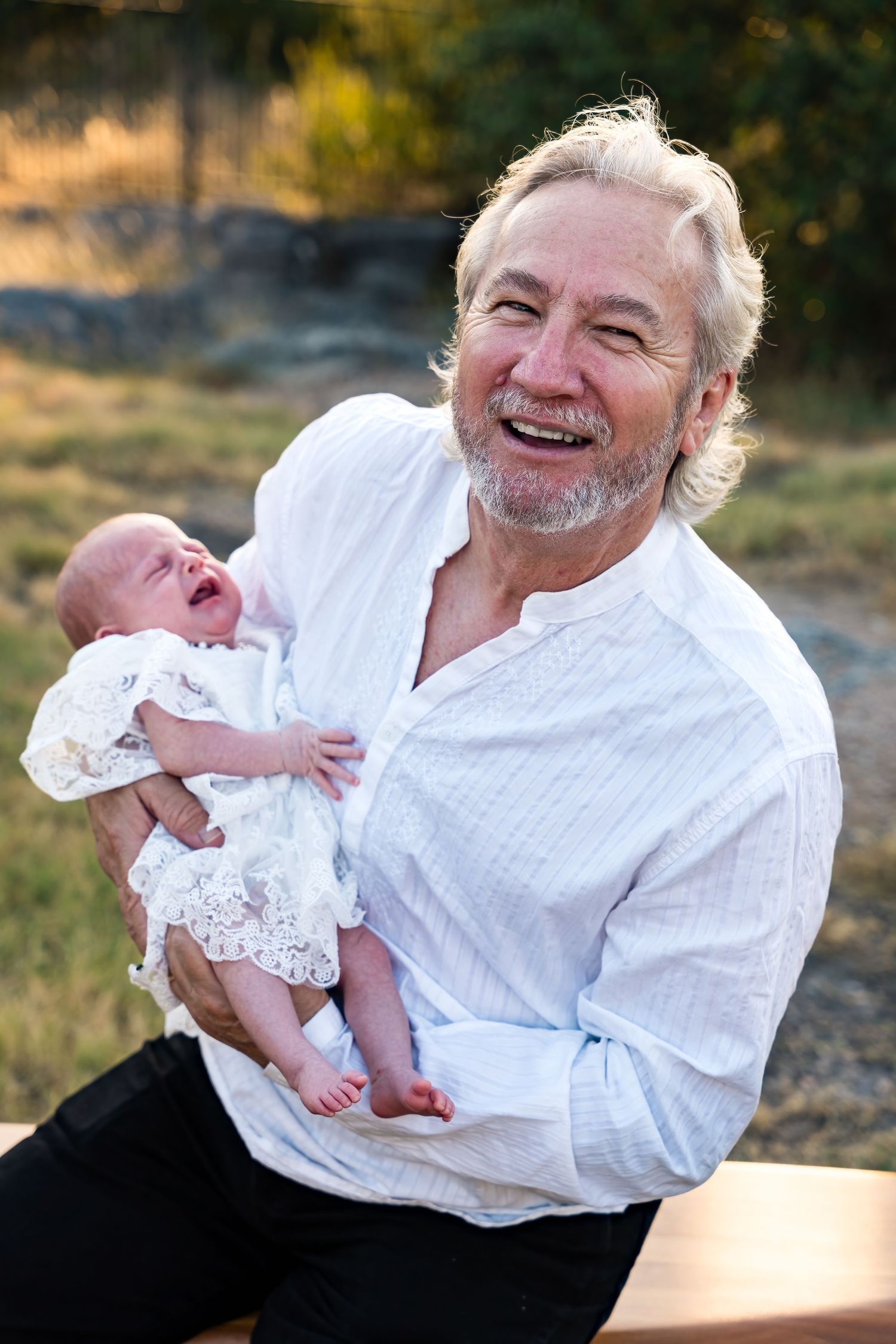 Candid moment of joy shared between baby and adult outdoors at sunset.