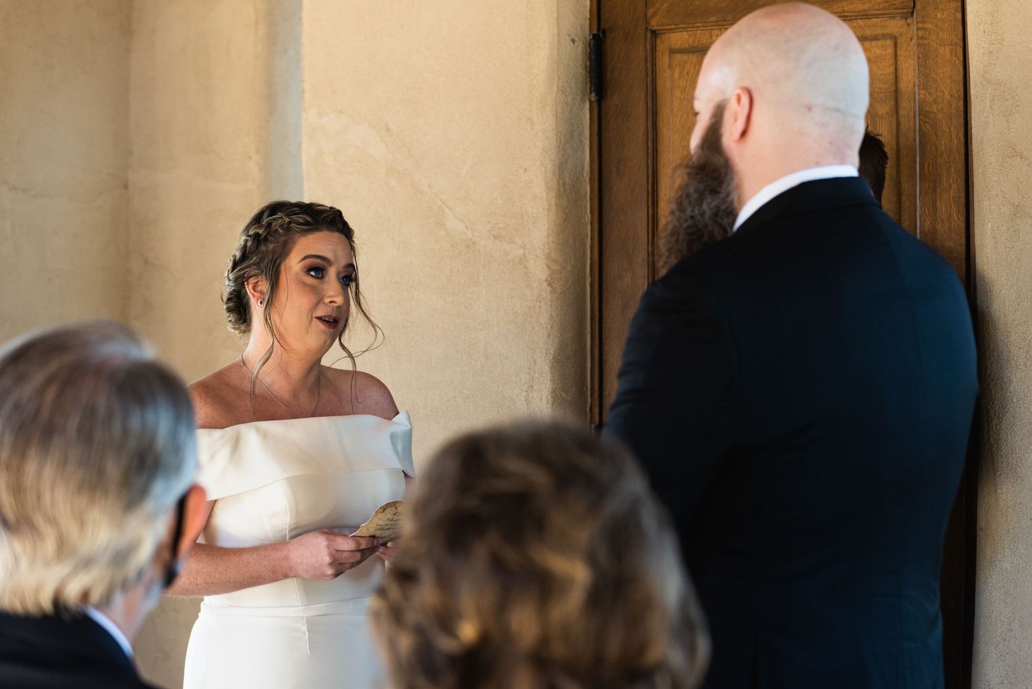 Intimate wedding ceremony with couple exchanging vows in front of wooden doors.