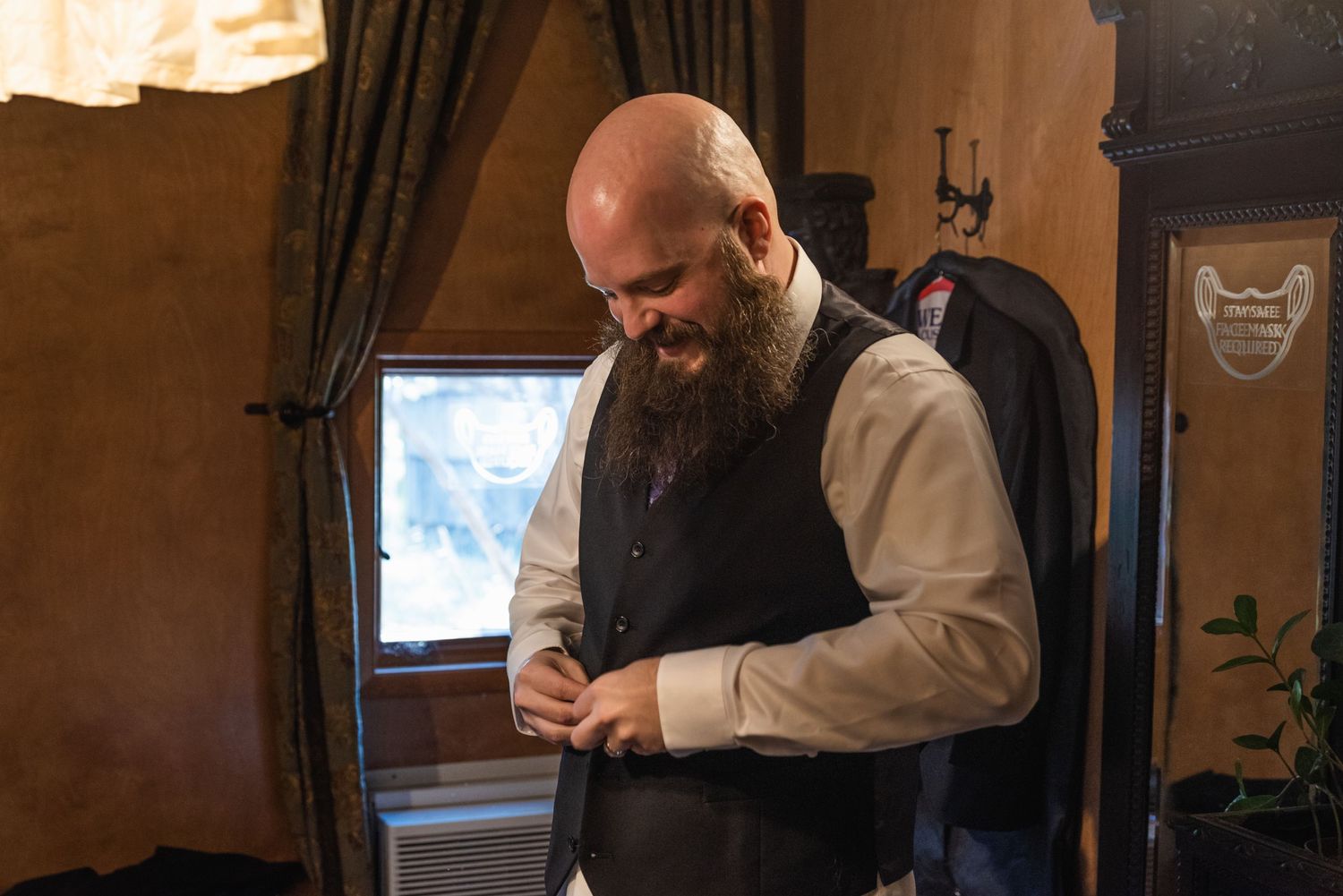 Person in formal vest and dress shirt adjusts attire while getting ready.
