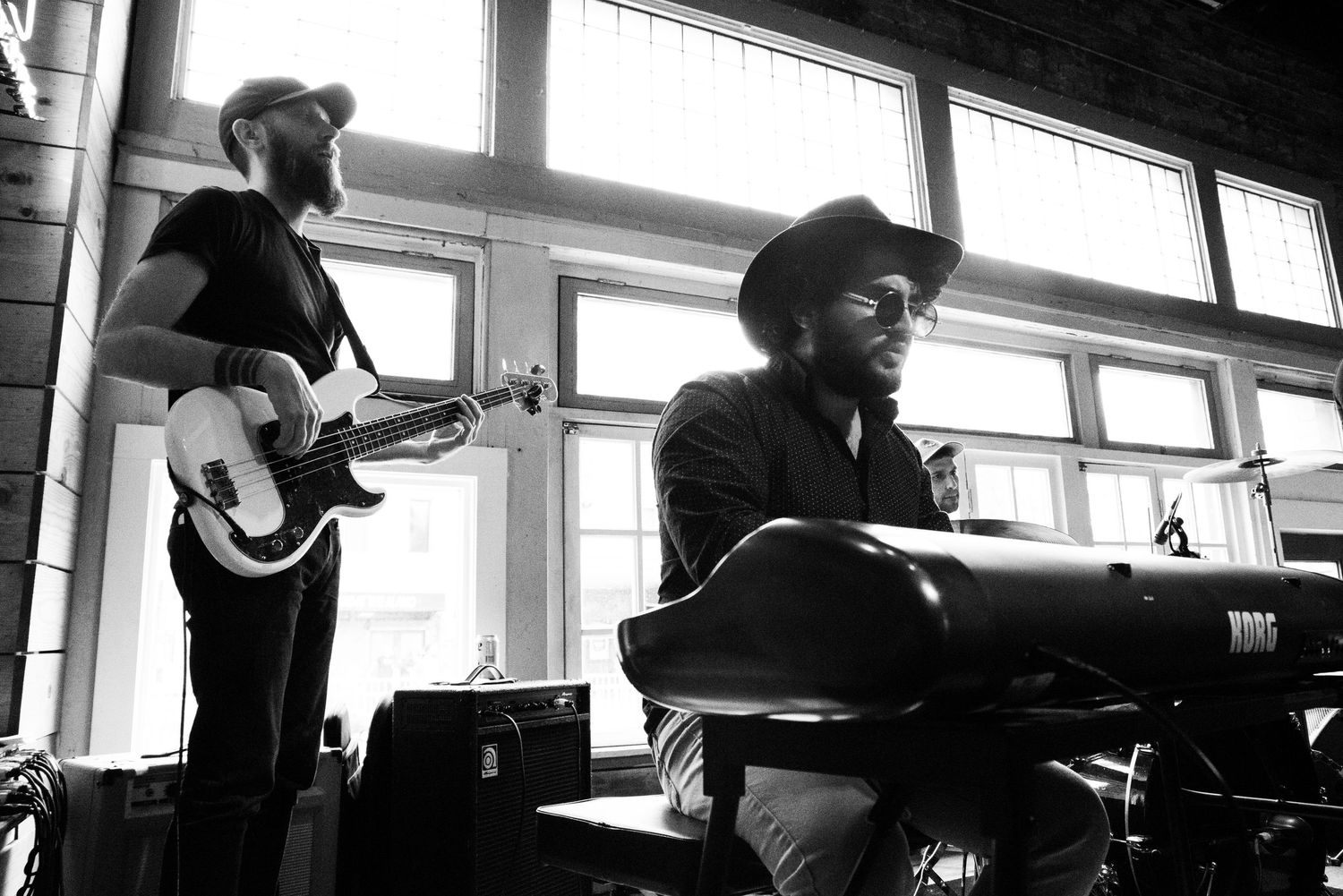 Musicians performing in a bright room with natural light streaming through windows.