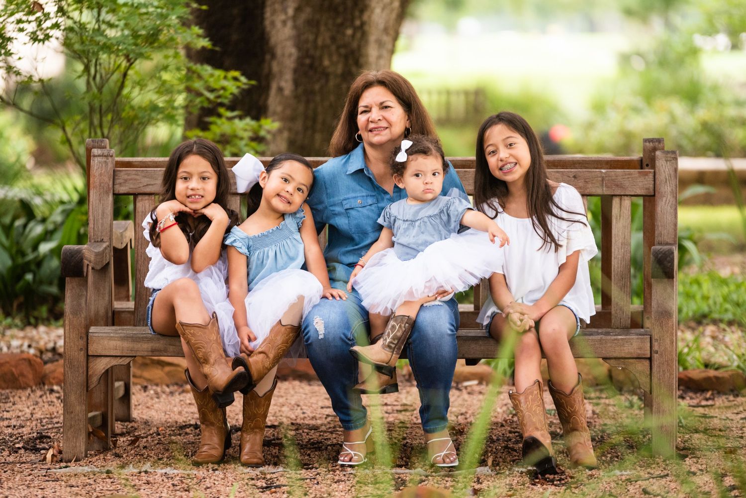 A family poses together on a wooden bench in a park setting wearing coordinated outfits.
