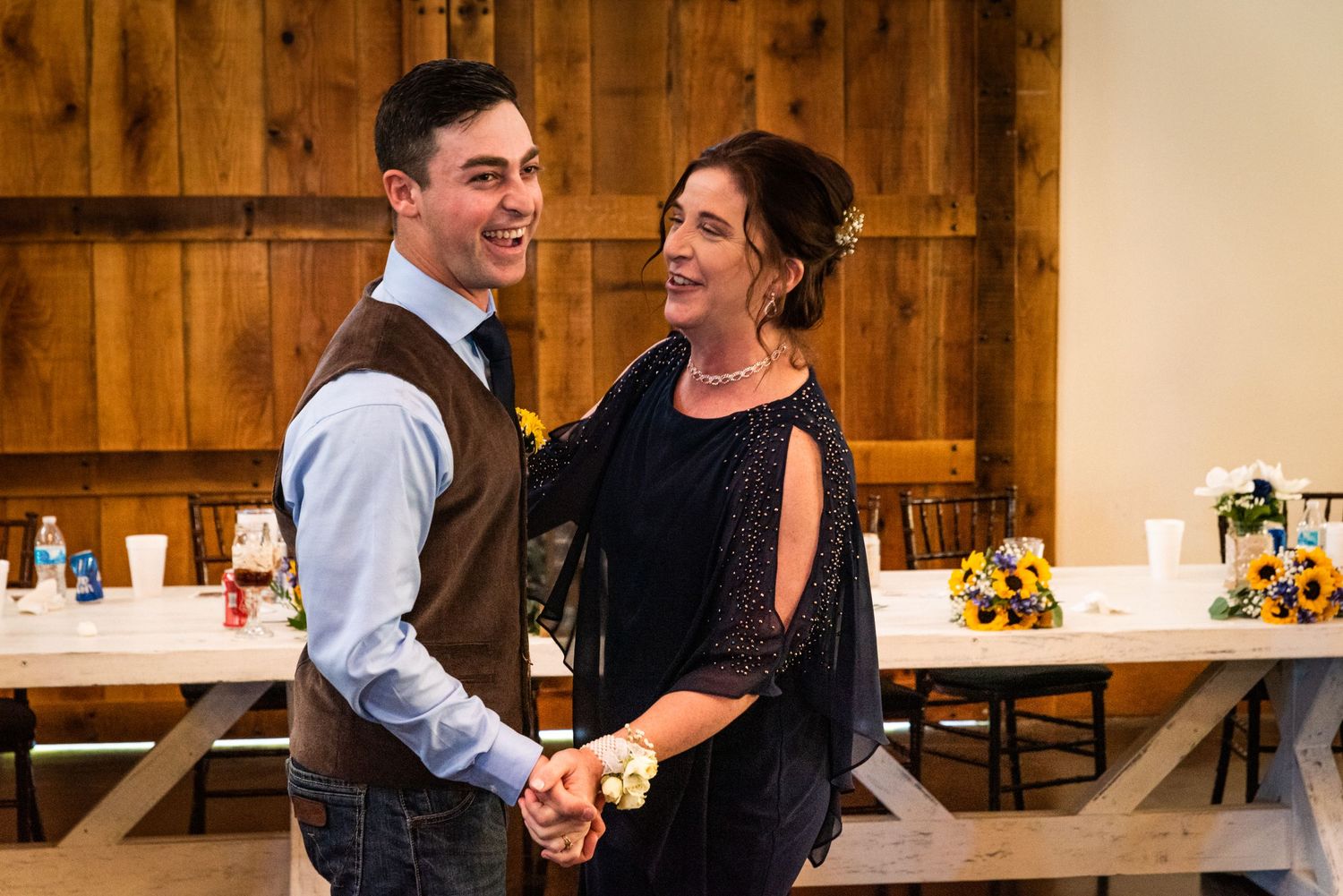 A couple shares a joyful dance moment together at a rustic wedding reception venue.