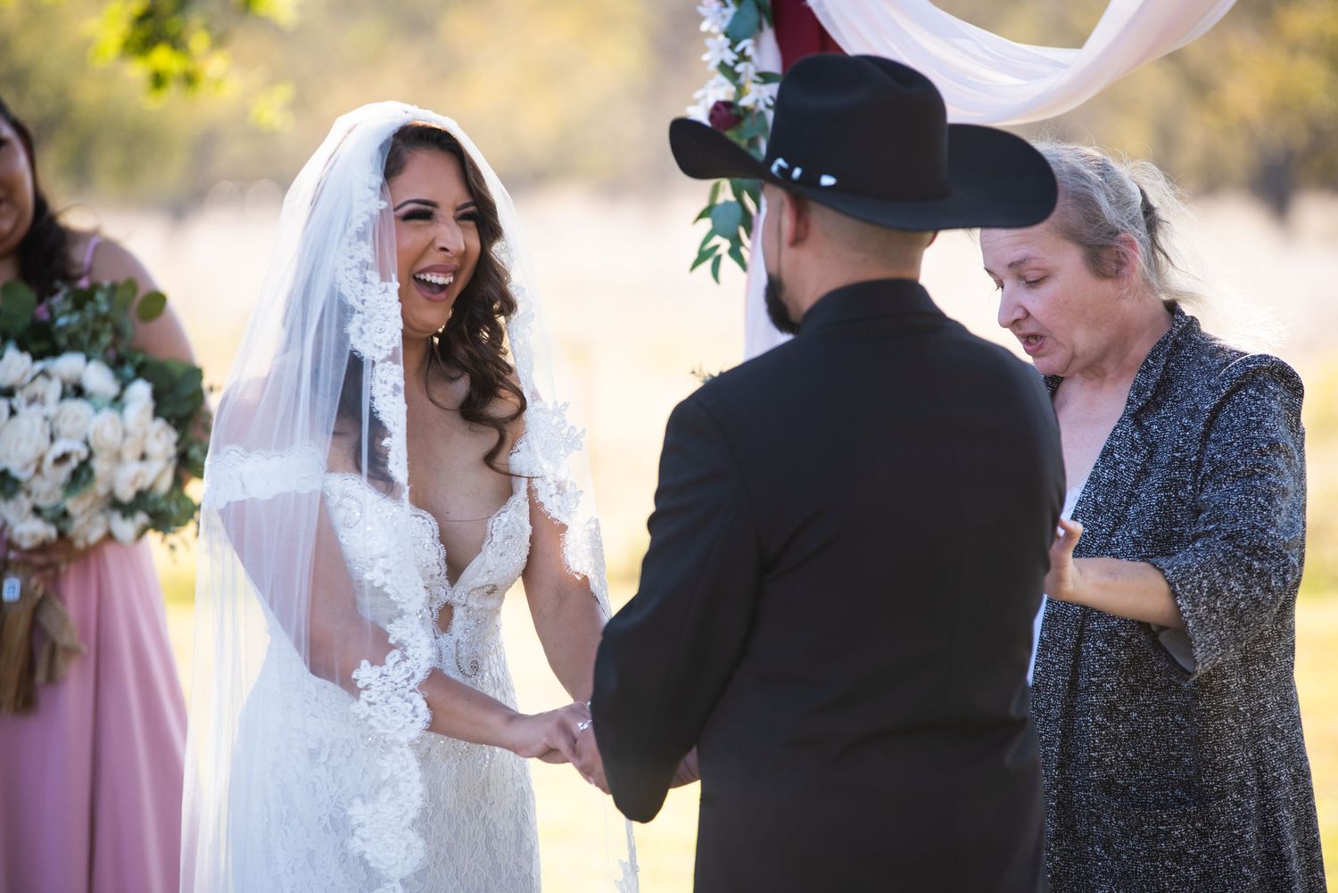 Outdoor wedding ceremony in progress with attendees watching the exchange of vows.