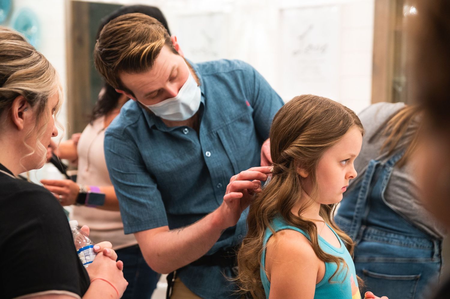 A stylist works on a client's hair during wedding preparations.
