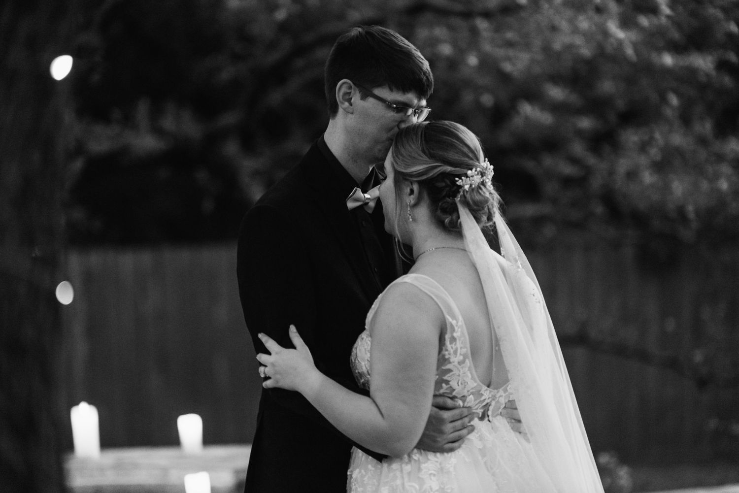 A romantic black and white wedding moment captured during an evening outdoor reception.