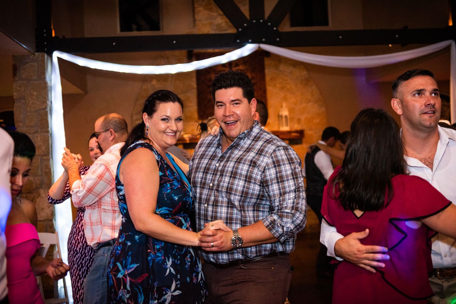 Couples dancing together at a casual wedding reception under white fabric decorations.