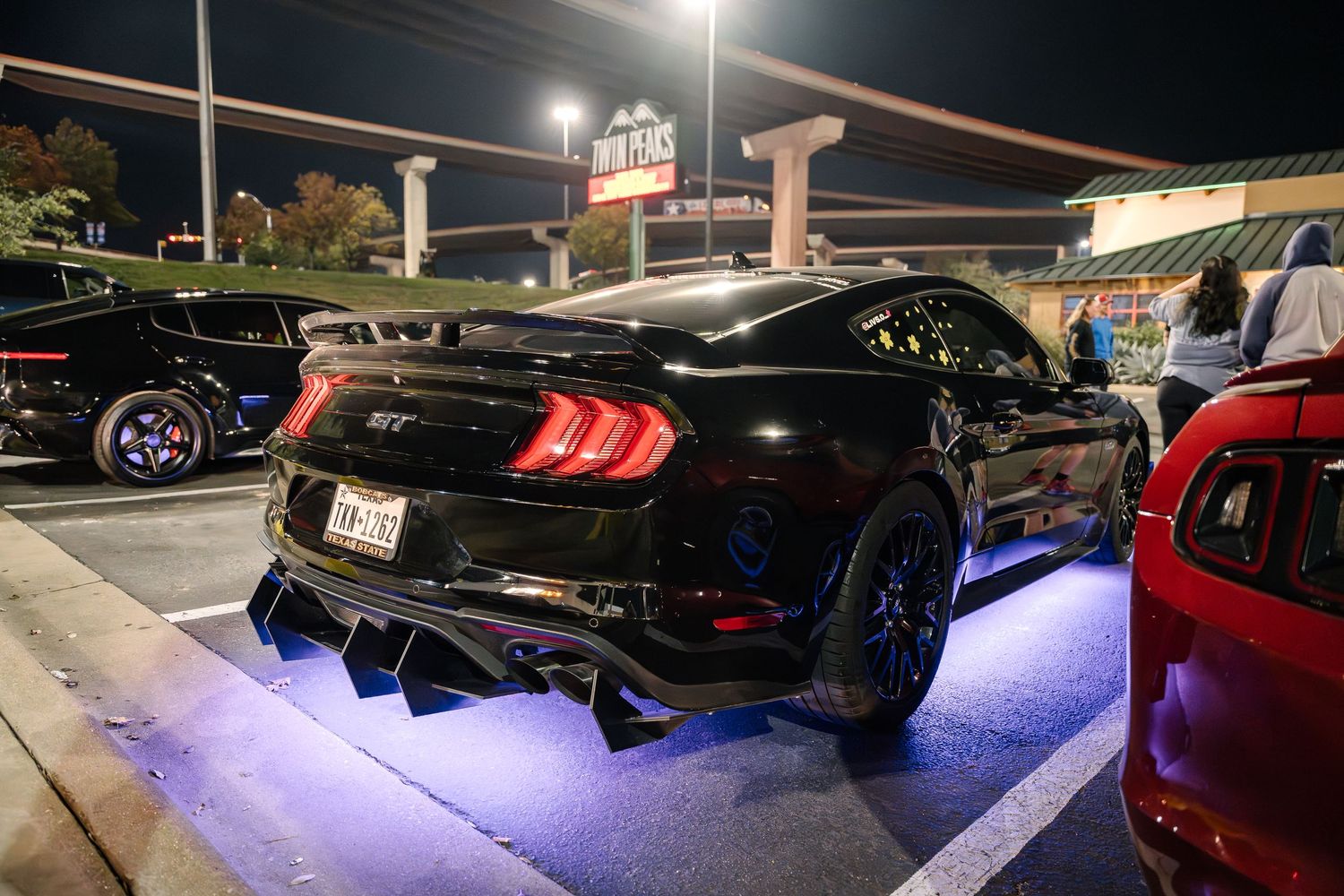 Modified Ford Mustang with custom LED underglow lighting and aftermarket exhaust system.