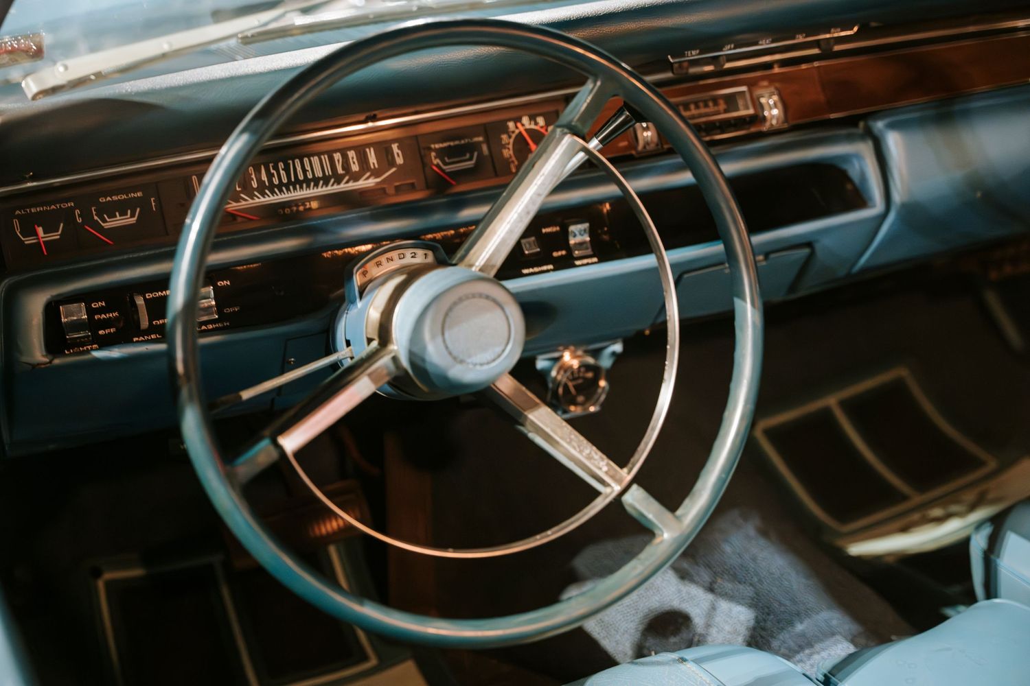 Vintage steering wheel and dashboard interior of a classic car.