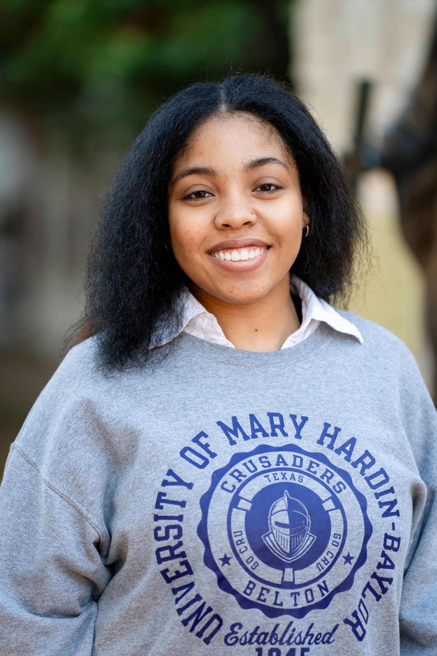 Close-up portrait of graduate wearing University of Mary Hardin-Baylor sweatshirt.