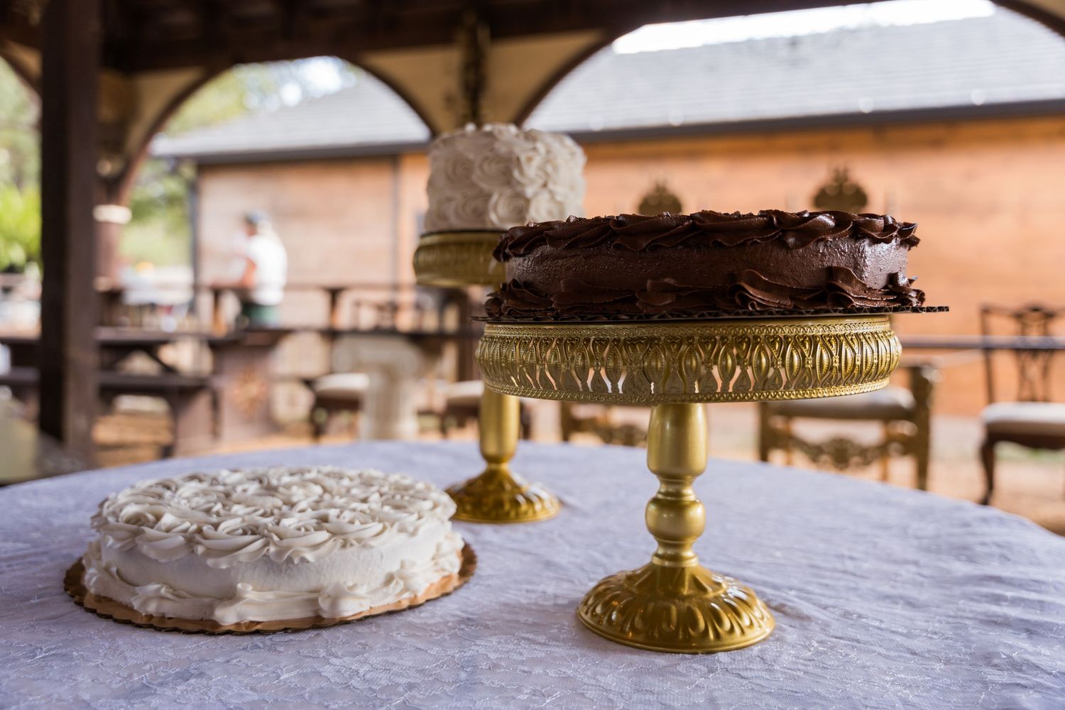 A series of elegant gold cake stands displaying delicate desserts and treats on a white tablecloth.